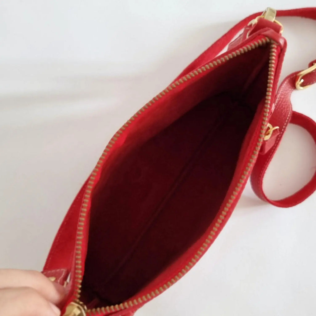 Close-up of small red leather crossbody with zip closure and long strap