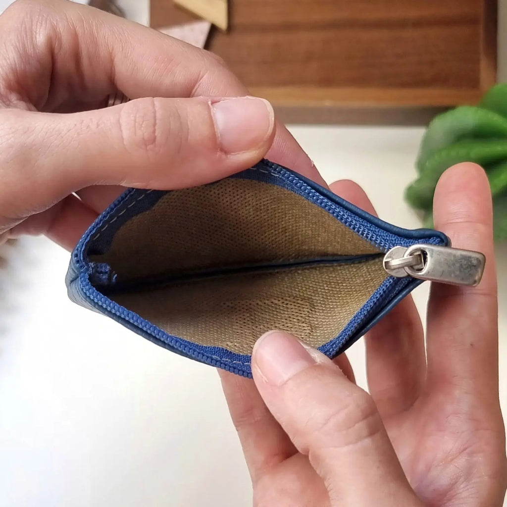 Detalle de cartera de cuero con cremallera dorada y grabado de iniciales