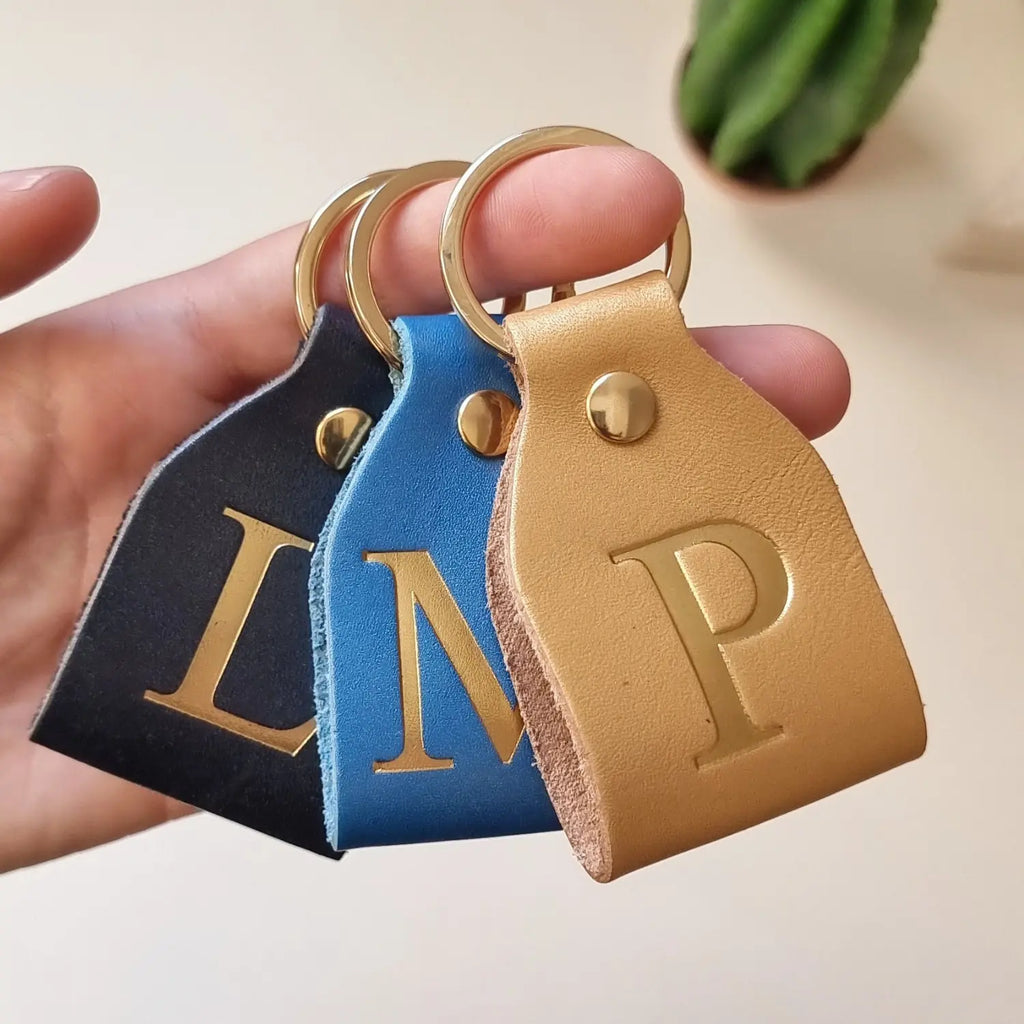 Close-up of small leather keychain with gold foil initial and ring