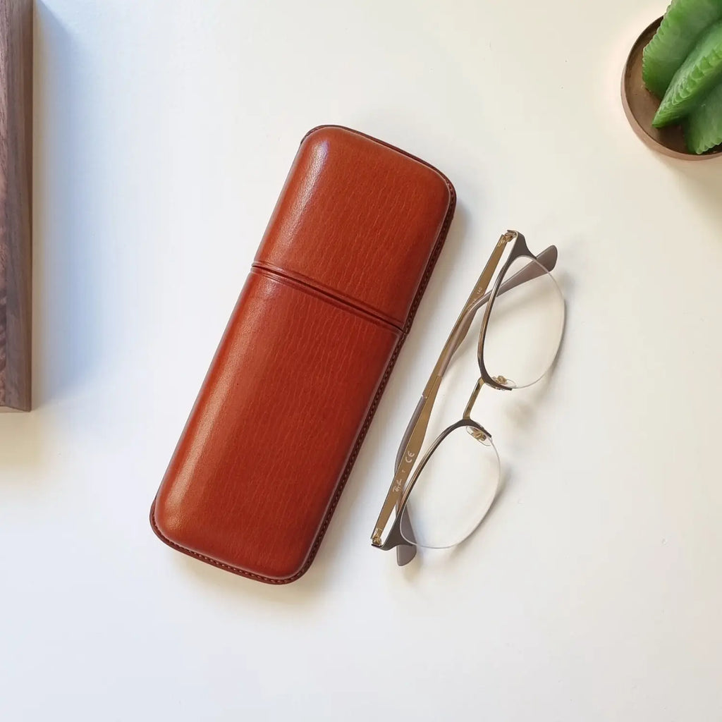 Funda de gafas hecha a mano en piel, sobre una superficie de piedra clara