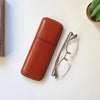 Funda de gafas hecha a mano en piel, sobre una superficie de piedra clara