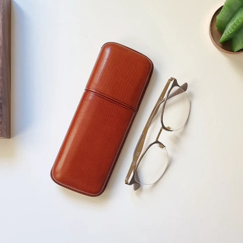 Funda de gafas hecha a mano en piel, sobre una superficie de piedra clara